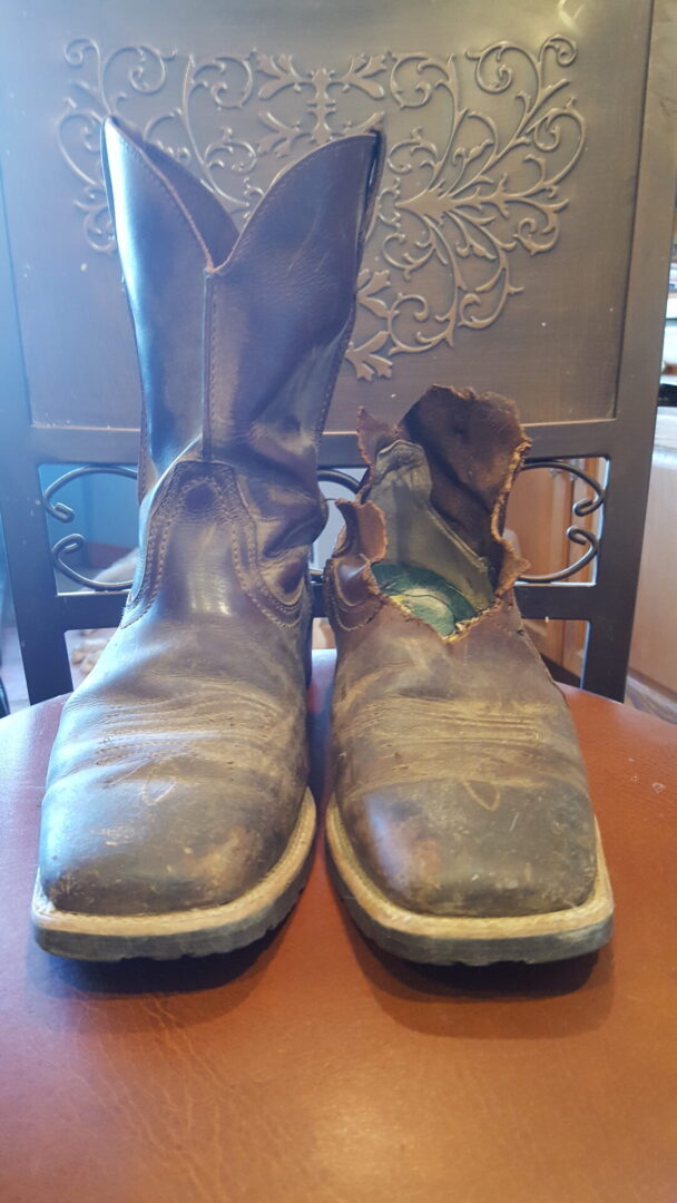 A pair of worn boots sitting on top of a wooden table.