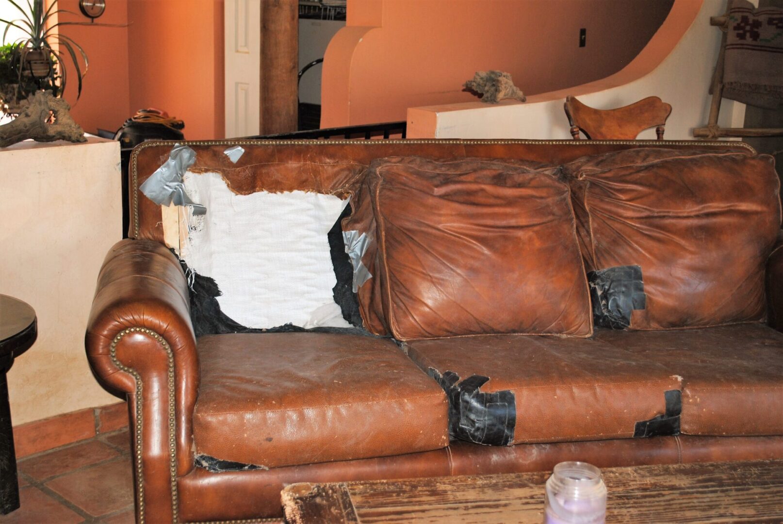 A brown leather couch with two pillows on it.